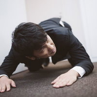 土下座をしながら次の予定に遅れないよう時計を気にするビジネスパーソンの写真