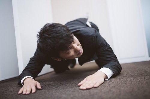 土下座をしながら次の予定に遅れないよう時計を気にするビジネスパーソン