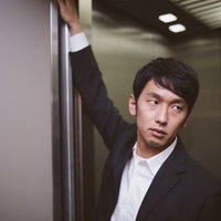 エレベーターのドアを押さえるデキる営業の写真