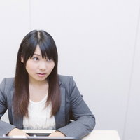 アイコンタクトでプレゼン中の部下に指示を出す先輩社員の写真