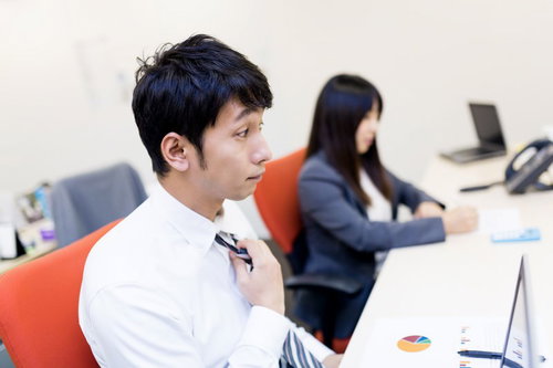 大事な会議前にデスクでネクタイを締めるビジネスパーソン