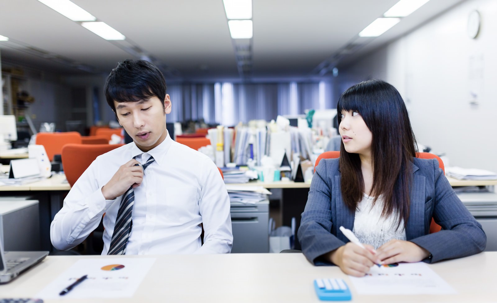 残業中にデスクで話し合う男女2人［モデル：大川竜弥 Lala］
