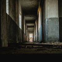 コンクリート造りの廃宿舎通路 薄暗く瓦礫が散乱した廃墟の長い廊下の写真