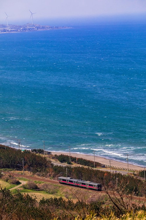 春がすみに霞む日本海をゆく羽越線の海岸線風景