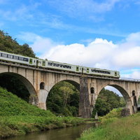 釜石線が走る岩手県のめがね橋、石造りのアーチ橋を電車が渡るの写真
