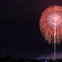 夜空に咲く遠くの打ち上げ花火が放射状に広がる夏祭りの風景の写真