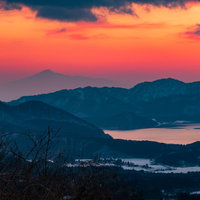 田沢湖と鳥海山が重なる夕焼けの山々の写真