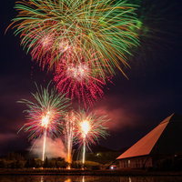 水田に反射する早苗饗（さなぶり）の花火の写真
