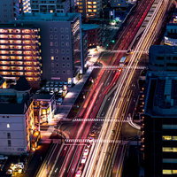仙台の夜の街並みを走る車の光跡、高層ビル群を彩るヘッドライトとテールランプの写真