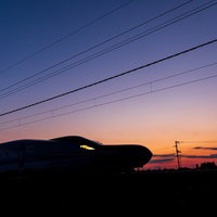 夕焼け空に浮かぶ特別急行列車E6系こまちのシルエットの写真