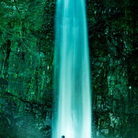 ライトアップされた玉簾の滝を眺めるシルエットの観光客の写真