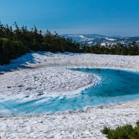 春の訪れと八幡平ドラゴンアイ、残雪に囲まれた青い沼の写真
