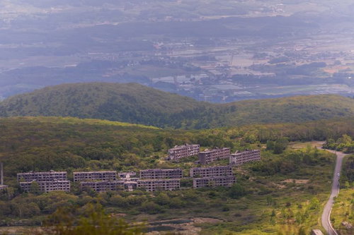 天空の廃墟と眼下に広がる街並み～山頂の崩壊建物群と市街地の対比