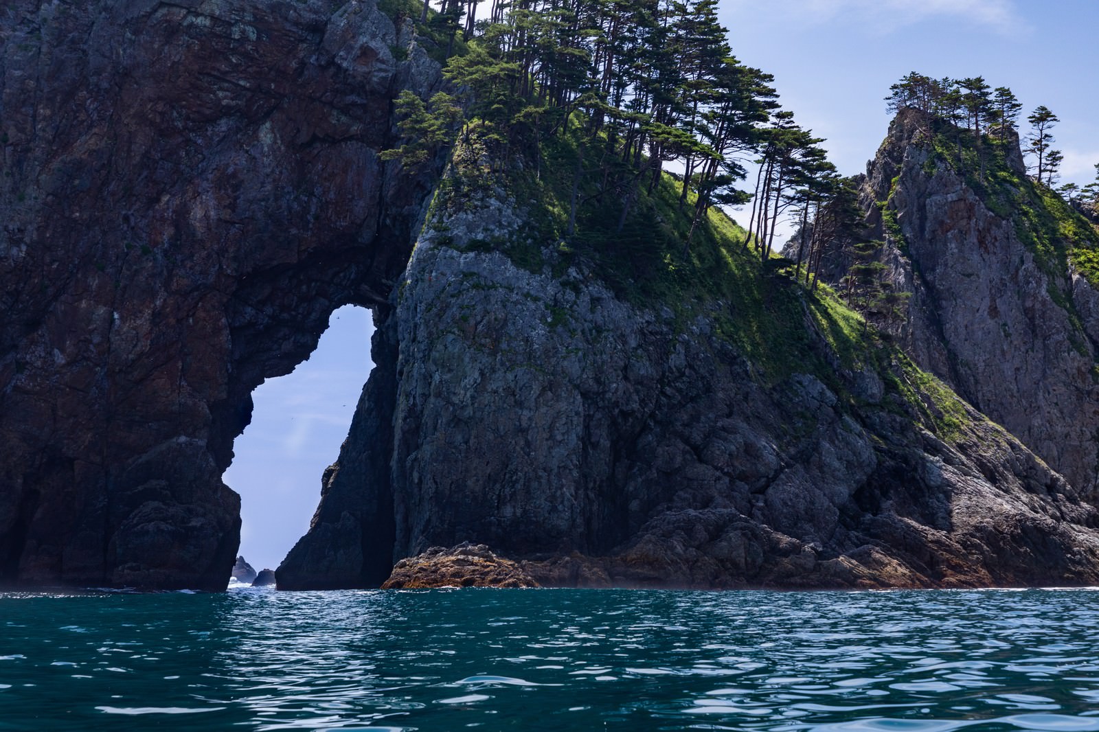 北山崎の断崖に形成された海食洞と自然アーチ、青い海と荒々しい岩肌