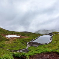 秋田駒ヶ岳の阿弥陀池と眼下に迫る雲の風景の写真