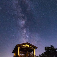 ラベンダー園の小屋と夜空に流れる天の川の星空風景の写真
