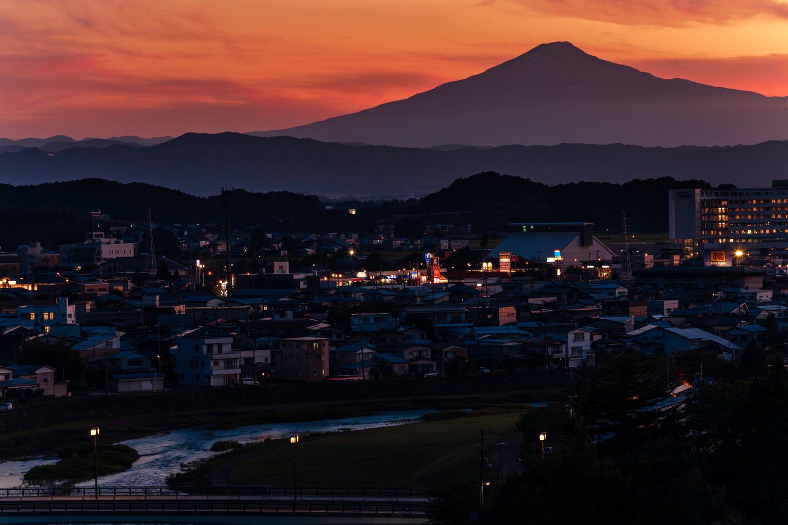 夕焼け空に浮かぶ鳥海山のシルエットと横手市街の夜景