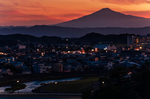 夕焼けに染まる横手市街と鳥海山のシルエット