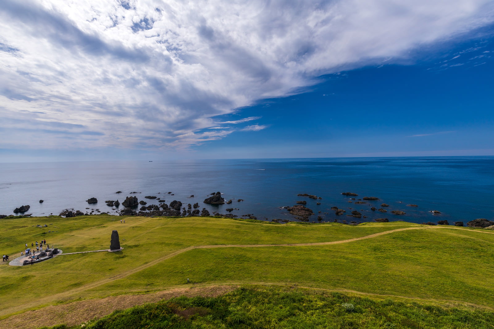 入道崎の緑の草原と青い日本海の景観
