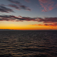 夜明け前の日本海に広がるオレンジ色の朝焼けの写真