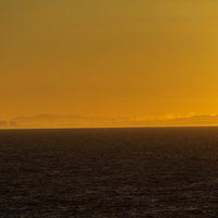 朝靄の中に浮かびあがる風車群と朝焼けの海の写真