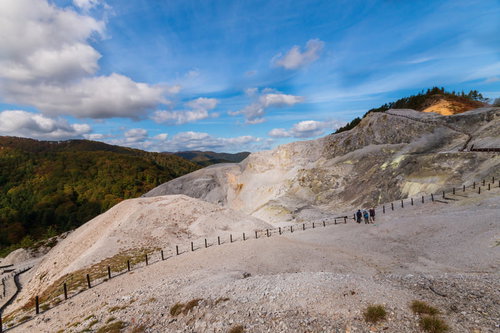 広大な川原毛地獄の白い岩肌を歩く登山者たち
