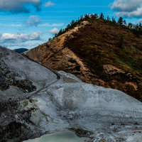 不気味に感じる灰白色の川原毛地獄と緑色の池の写真