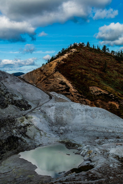不気味に感じる灰白色の川原毛地獄と緑色の池