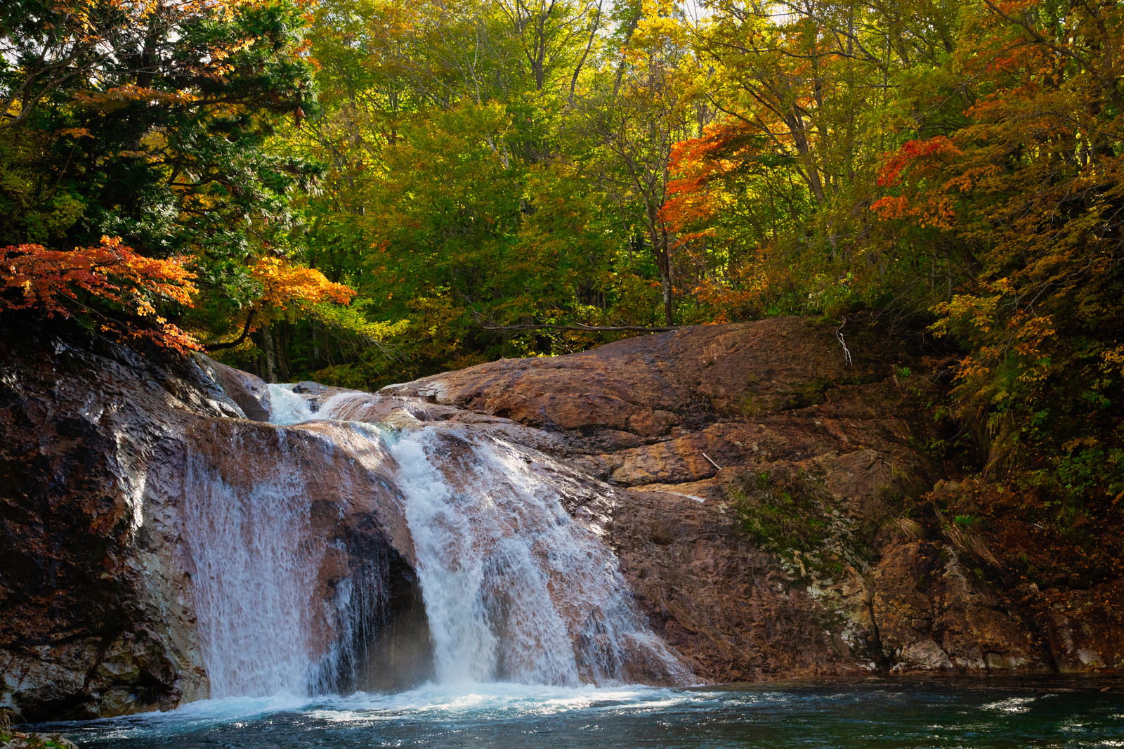 紅葉した木々に囲まれた渓谷で岩場を流れ落ちる滝