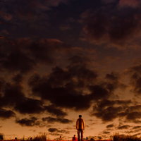 階段のある土手の上から夕焼けを眺める男性のシルエットの写真