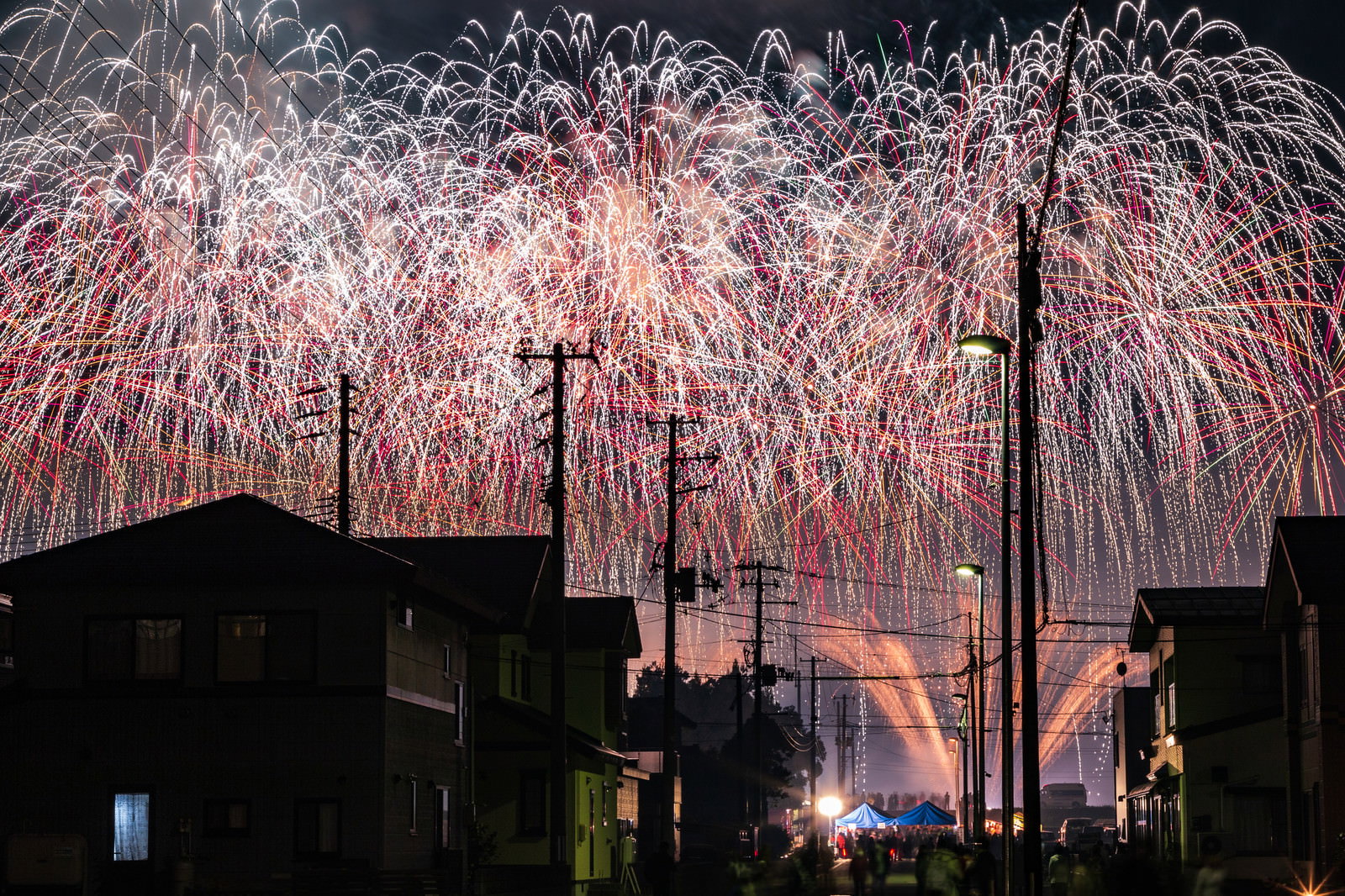 夜空に広がるカラフルな打ち上げ花火と住宅街のシルエット
