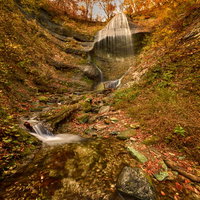 紅葉に染まる岩手県の渓谷、滝から続く清流と水の流れの写真