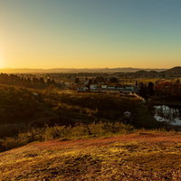 丘陵地帯に広がる町並みを染める夕焼けと夕日の写真