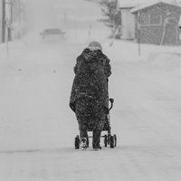 豪雪地帯の雪道をゆっくり歩く高齢女性の日常の写真