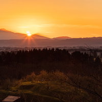 鳥海山の裾野に沈むオレンジ色の夕日と林檎畑の写真