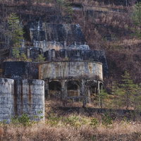 土畑鉱山跡の廃墟群、山奥に放置されたコンクリート貯蔵タンクと石造り建物の写真