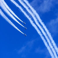 青空で宙返りを決めるブルーインパルスの編隊飛行の写真