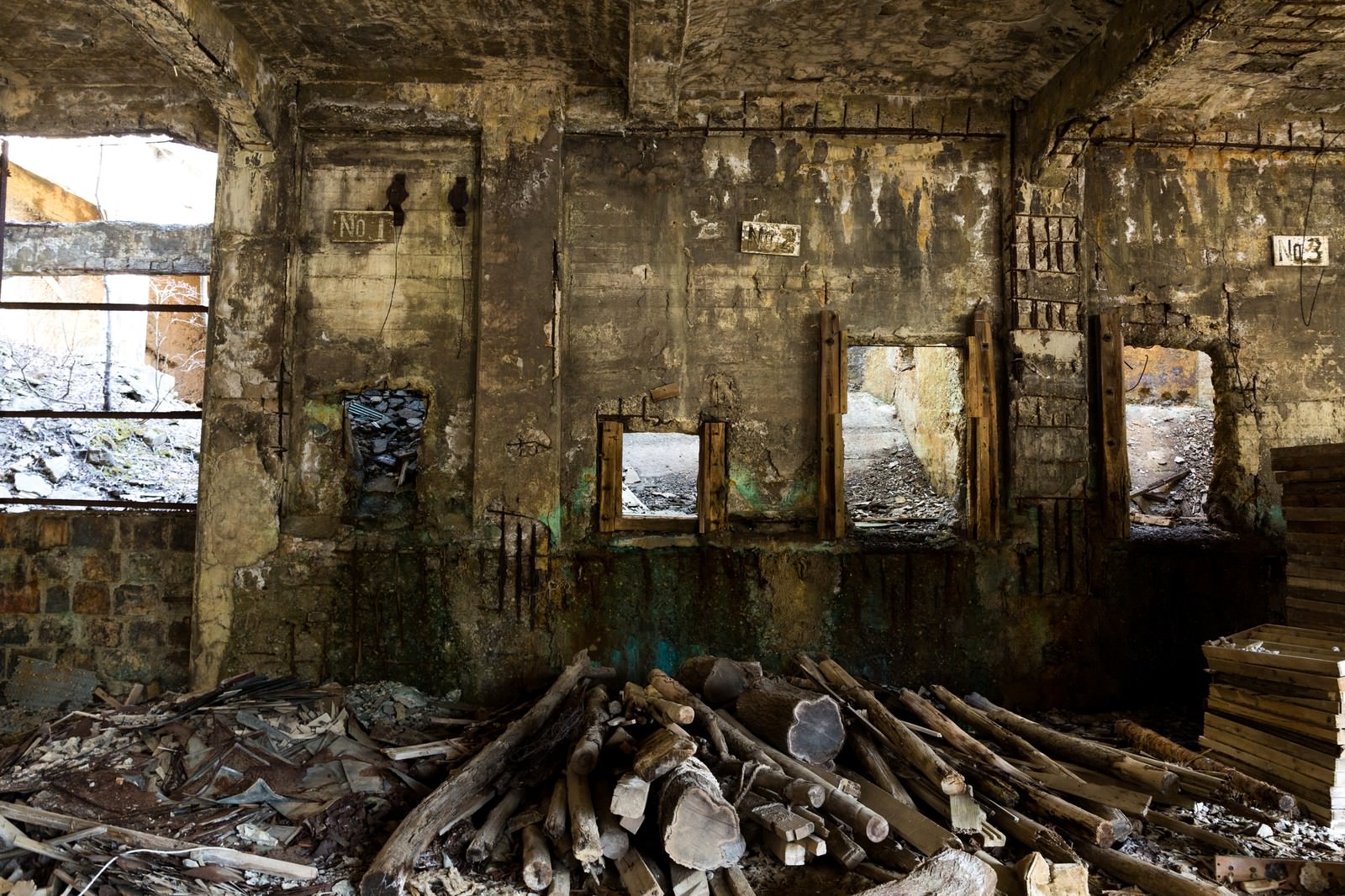 苔やカビで覆われたコンクリート壁の廃鉱山坑道に積まれた朽ちた木材