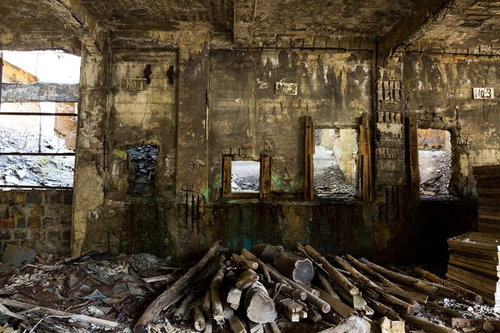 木材が積まれた廃墟の地下坑道、苔とカビに覆われたコンクリート壁