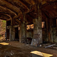 朽ち果てた木造建築の内部と瓦礫が散らばる廃鉱山の作業現場の写真