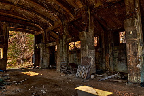 朽ち果てた木造建築の内部と瓦礫が散らばる廃鉱山の作業現場