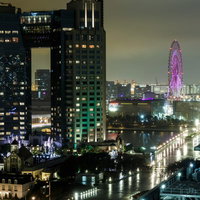 お台場の雨の夜に紫色にライトアップされた観覧車と高層ビル群の写真