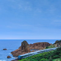 日本海を走るローカル線と岩礁、海岸線の景観の写真
