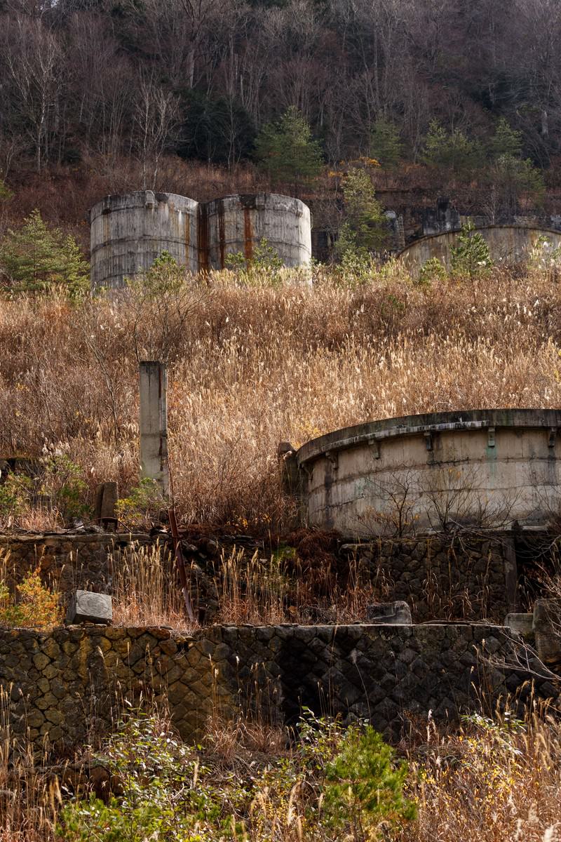 廃鉱山に放置された錆びた貯蔵タンクと枯れ草