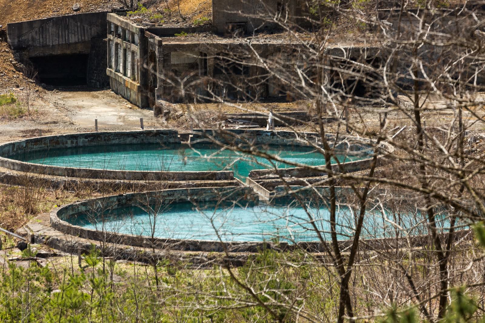 尾去沢鉱山の廃坑に残る青緑色の水槽と朽ちた建造物