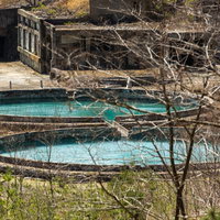 尾去沢鉱山の廃墟に残る青緑色の水槽と鉱山施設跡の写真