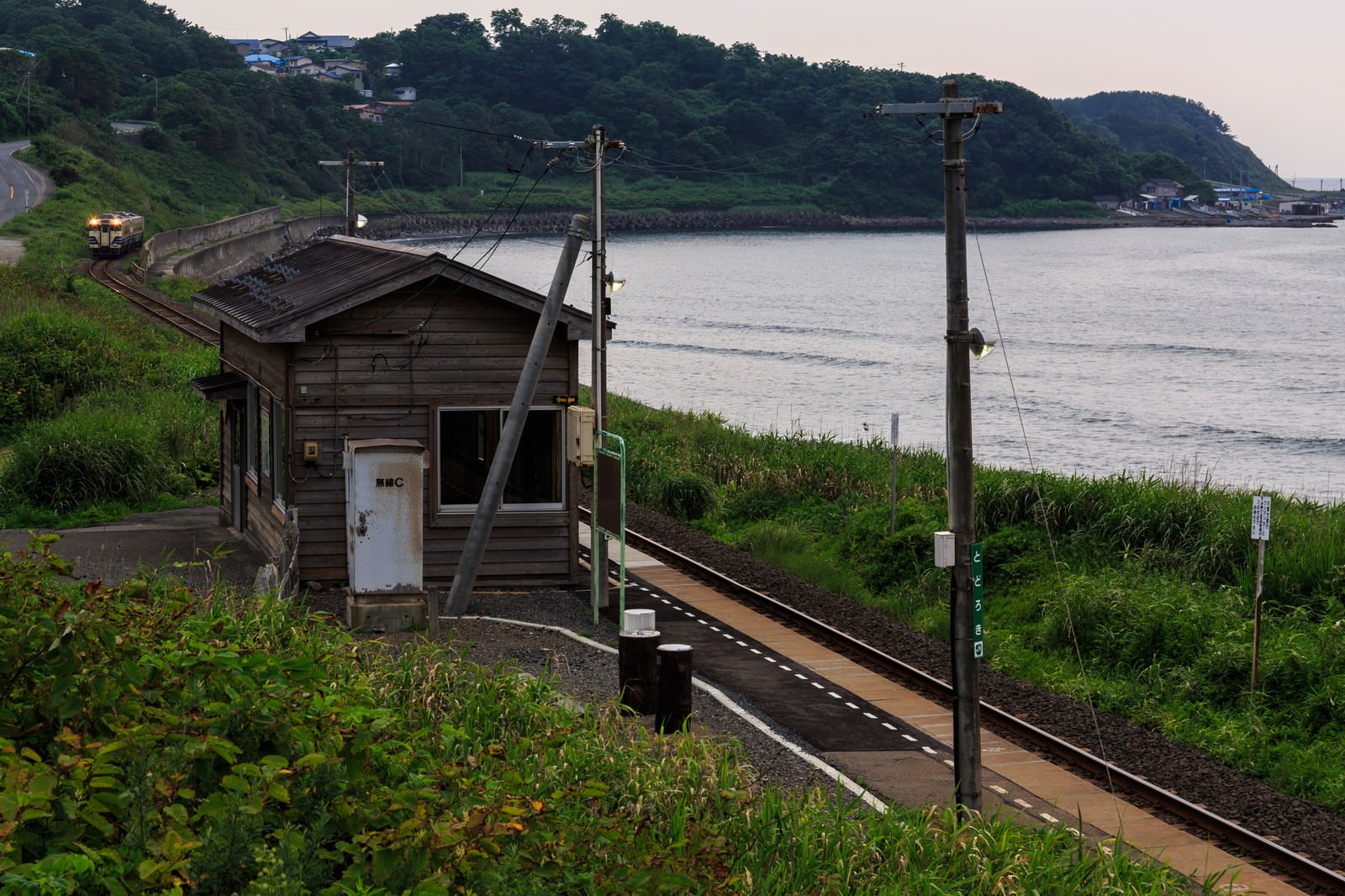 海沿いの木造無人駅舎と線路の風景