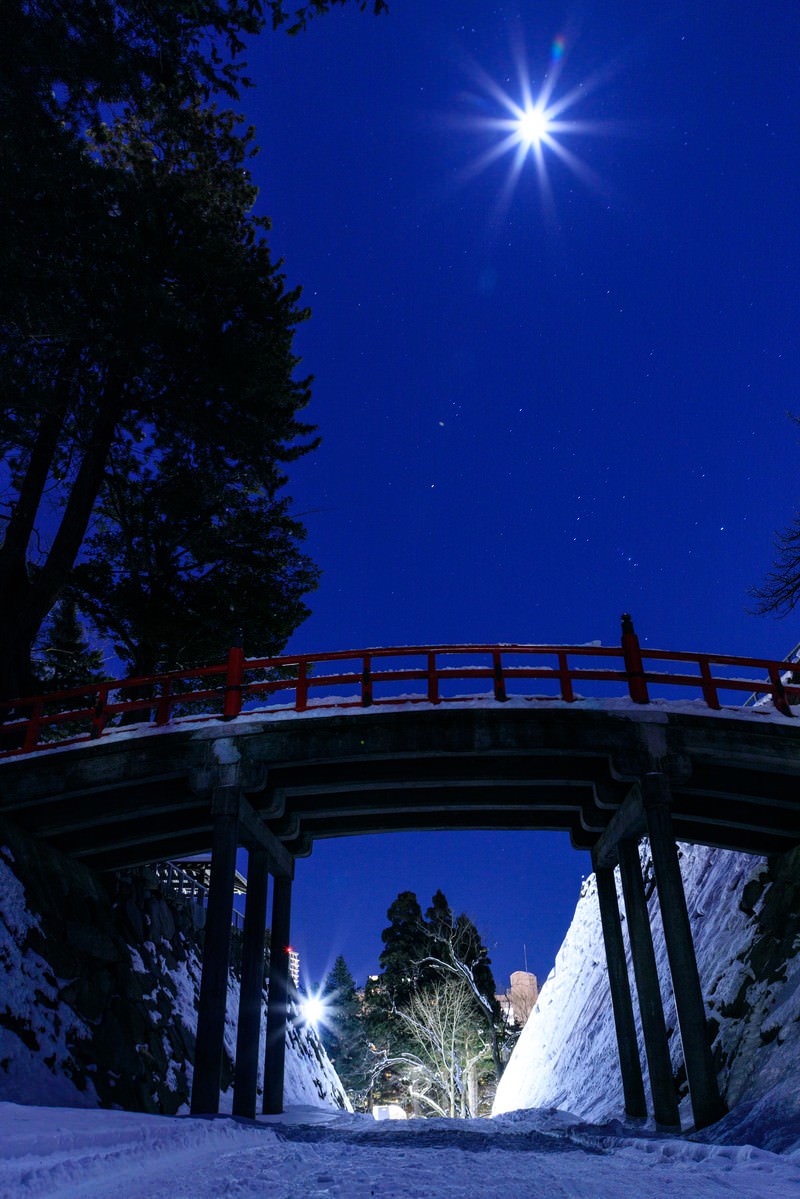 ピンクにライトアップされたアーチ橋と雪の夜景
