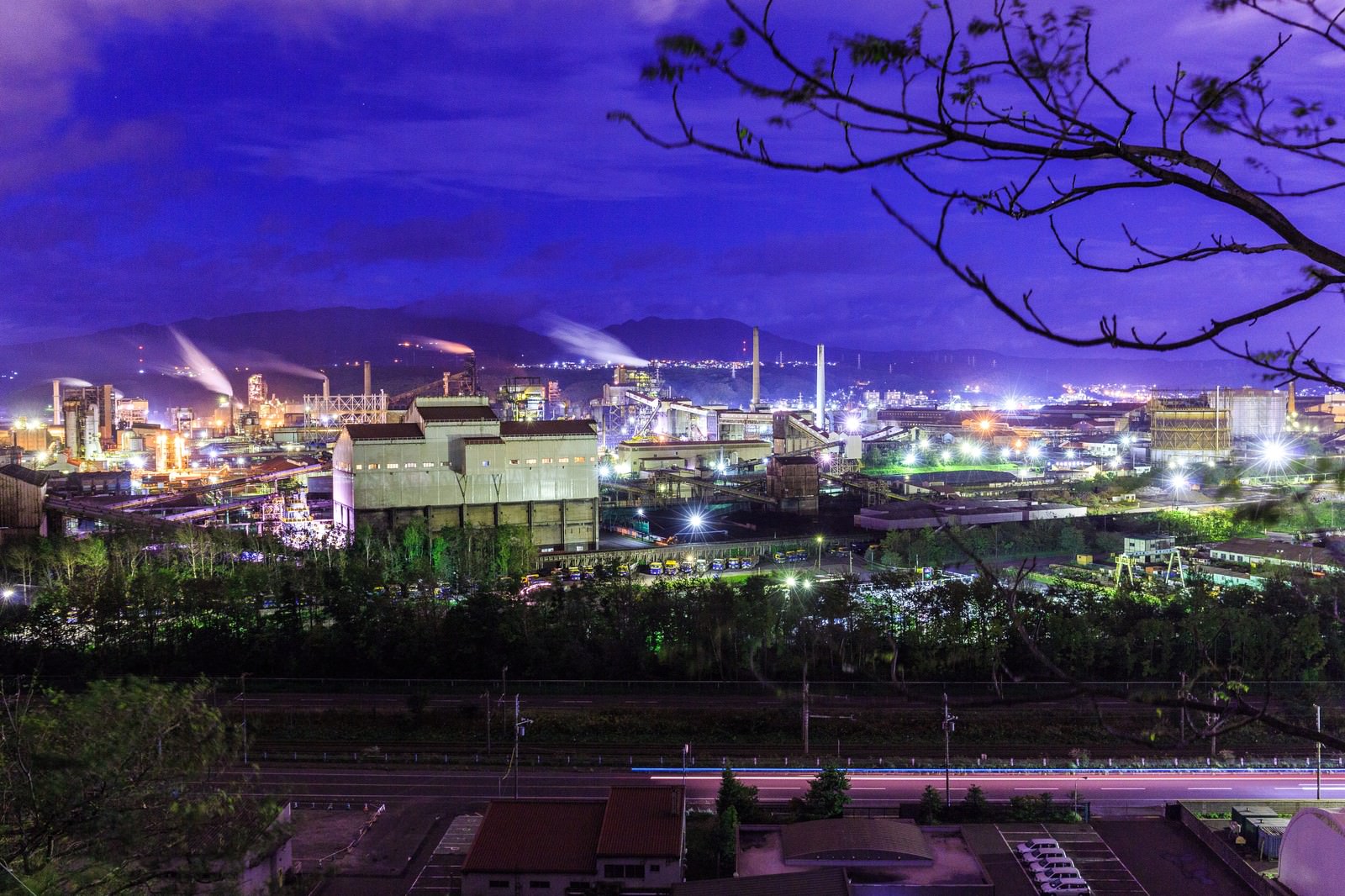 紫色の夜空の下で光る室蘭の工場群と煙突の夜景