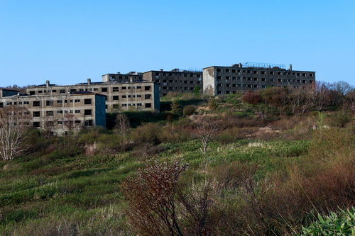 高台に建つ廃墟の集合住宅、斜面に立ち並ぶ団地建物群の写真